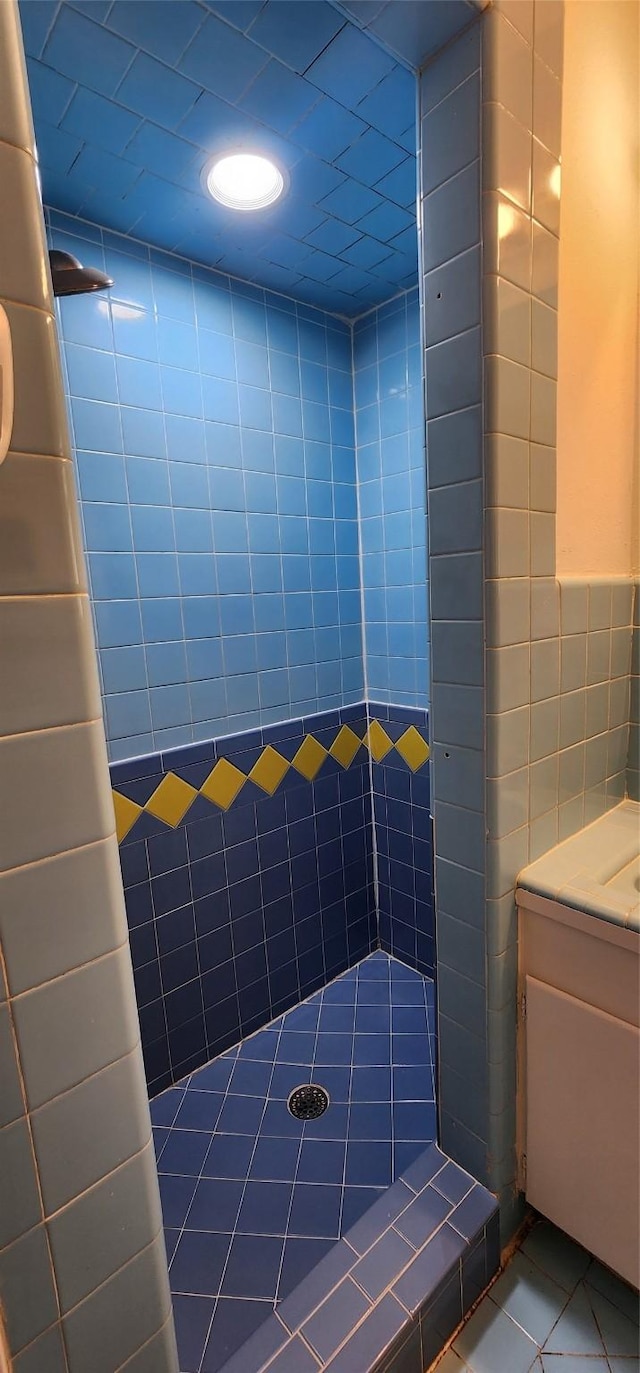 bathroom featuring tile patterned flooring, a tile shower, and tile walls