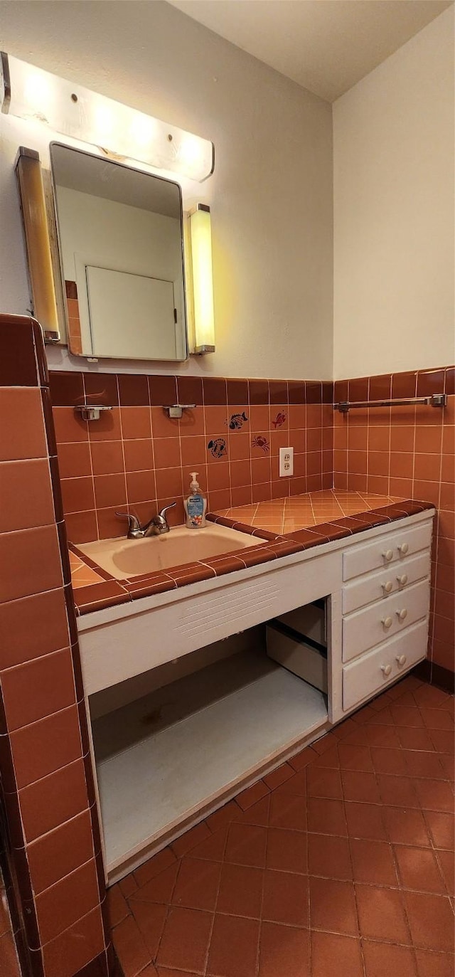 bathroom featuring vanity, wainscoting, tile patterned floors, and tile walls