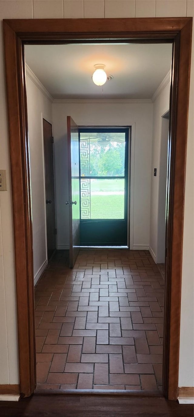 doorway with baseboards, ornamental molding, and brick floor