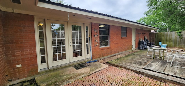 exterior space featuring brick siding, fence, french doors, and a deck
