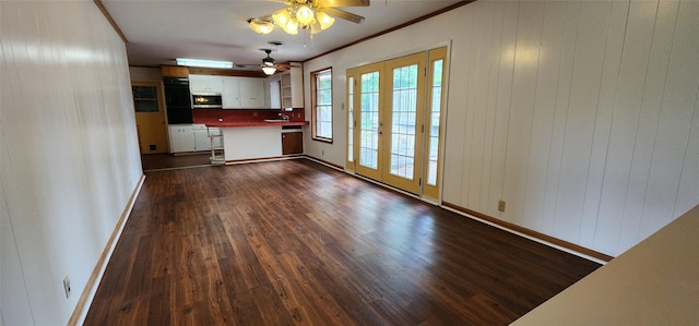 unfurnished dining area with a sink, ornamental molding, a ceiling fan, baseboards, and dark wood-style floors