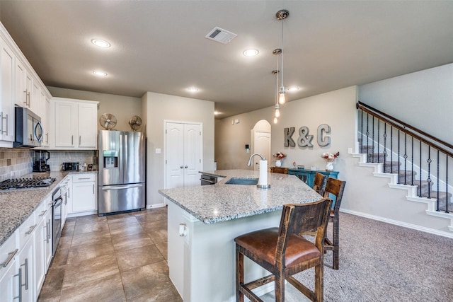 1821 Beacon Beach Way, Wylie, TX 75098 - kitchen featuring stainless steel appliances, a sink, a breakfast bar area, a kitchen island with sink, and white cabinetry