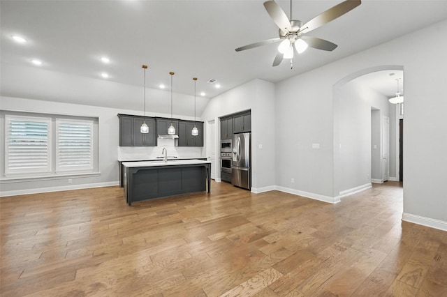 kitchen with ceiling fan, appliances with stainless steel finishes, arched walkways, light countertops, and open floor plan
