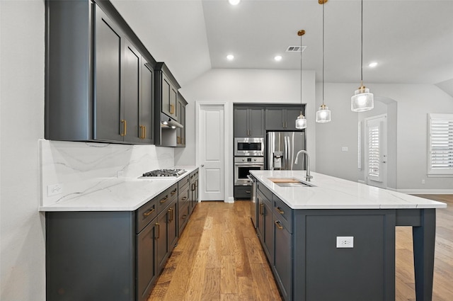 kitchen featuring a sink, light wood-style flooring, appliances with stainless steel finishes, and vaulted ceiling