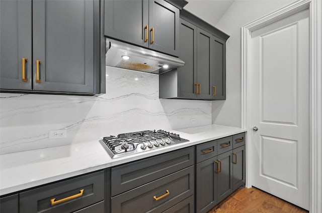 kitchen featuring gray cabinets, under cabinet range hood, and stainless steel gas stovetop