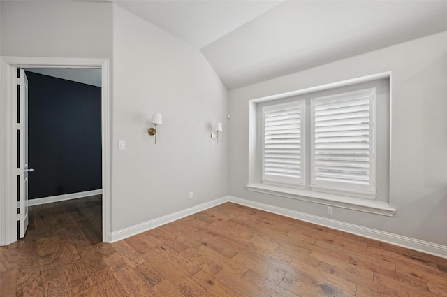 unfurnished room featuring baseboards, wood finished floors, and vaulted ceiling