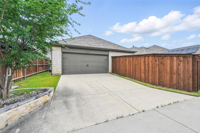 garage featuring concrete driveway and fence