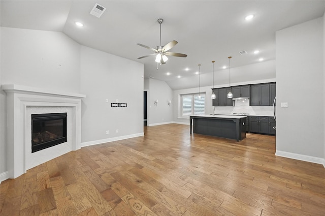 kitchen featuring ceiling fan, light wood-style floors, light countertops, open floor plan, and lofted ceiling