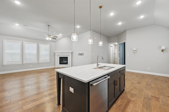 kitchen with a sink, an island with sink, vaulted ceiling, and dishwasher