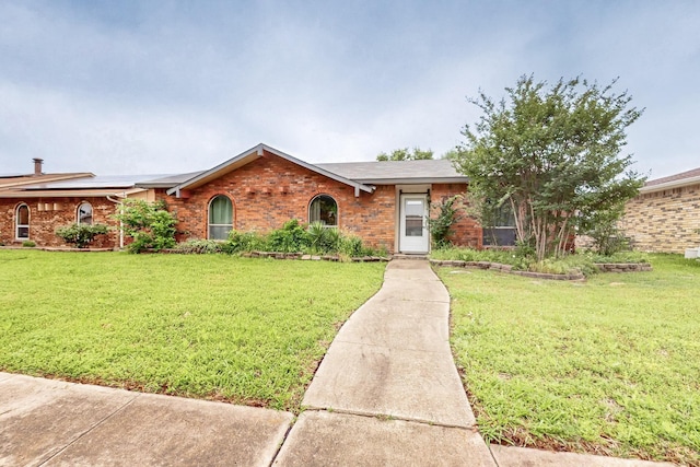 ranch-style home with a front yard and brick siding