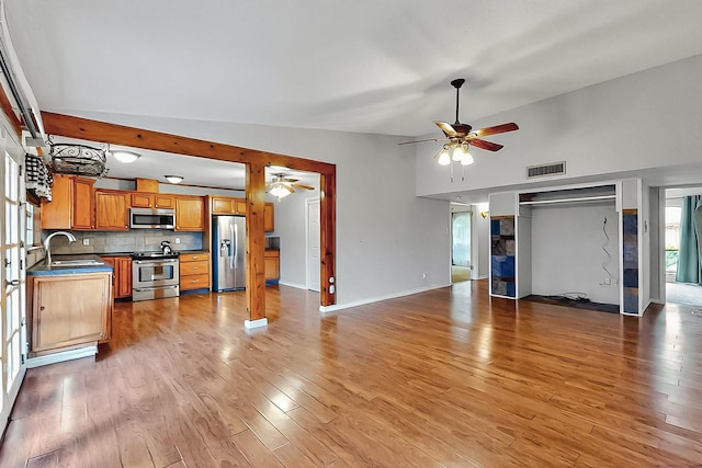 unfurnished living room featuring ceiling fan, visible vents, a sink, and light wood-type flooring