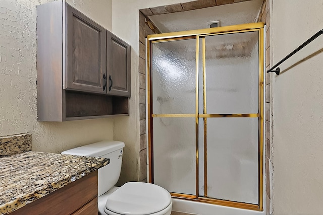 full bath featuring vanity, toilet, a textured wall, and a stall shower
