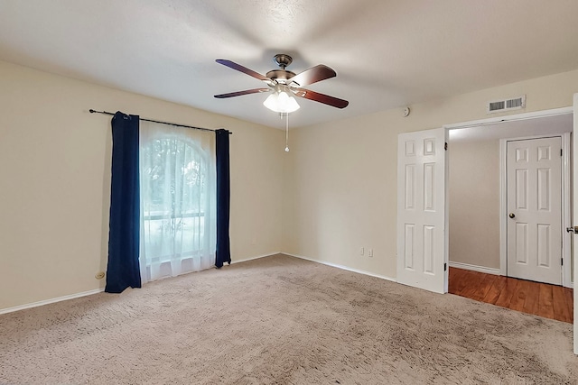 carpeted spare room with a ceiling fan, baseboards, and visible vents