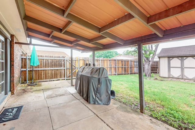 view of patio with an outdoor structure, a fenced backyard, a shed, and area for grilling