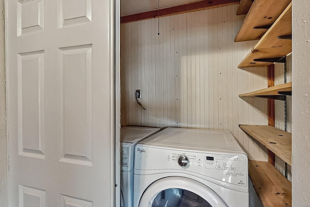 laundry room featuring washer and dryer, wooden walls, and laundry area