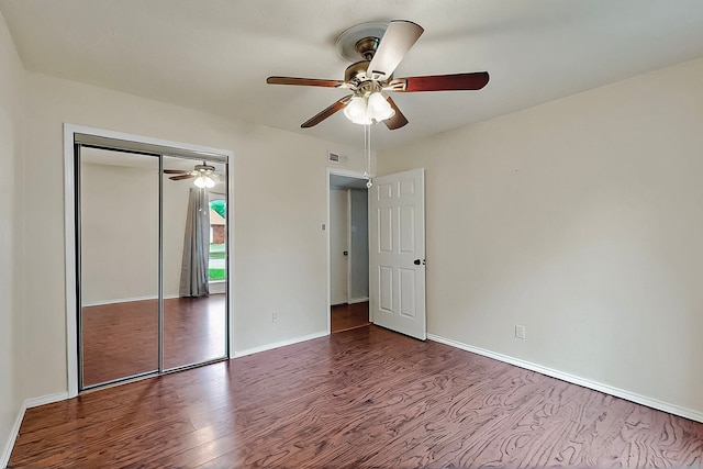 unfurnished bedroom with a ceiling fan, visible vents, wood finished floors, baseboards, and a closet
