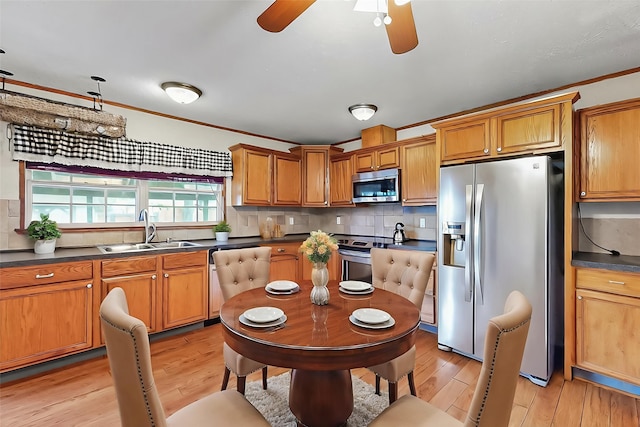 kitchen featuring a ceiling fan, dark countertops, a sink, light wood-style floors, and stainless steel appliances