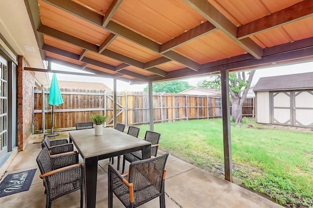 view of patio / terrace featuring a fenced backyard, outdoor dining space, an outdoor structure, and a storage shed