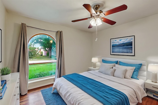 bedroom with ceiling fan, wood finished floors, and multiple windows