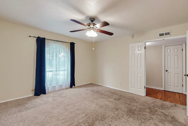 carpeted spare room with a ceiling fan, baseboards, and visible vents