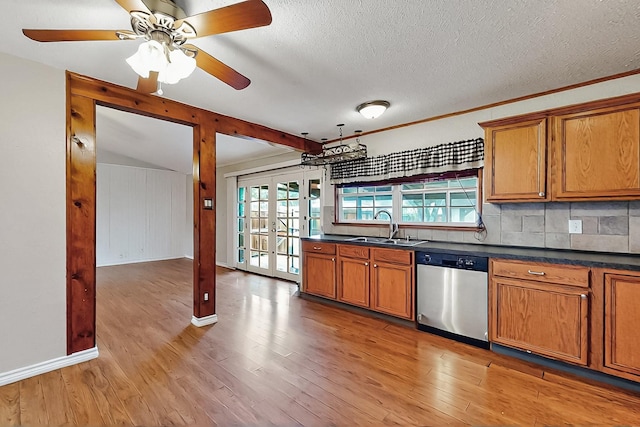 kitchen with dark countertops, light wood-type flooring, brown cabinets, dishwasher, and a sink