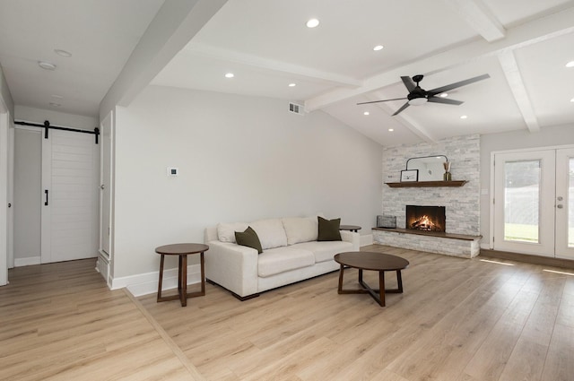 living area with a barn door, light wood finished floors, a ceiling fan, baseboards, and a fireplace