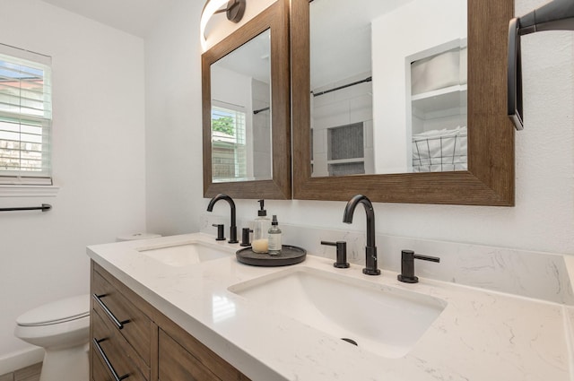 bathroom with double vanity and toilet