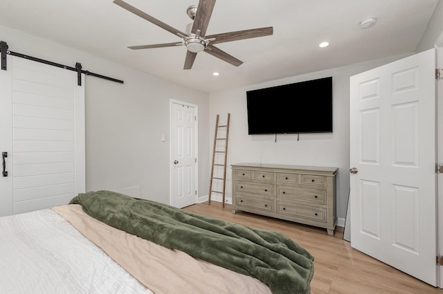 bedroom featuring a barn door, recessed lighting, light wood-type flooring, baseboards, and ceiling fan