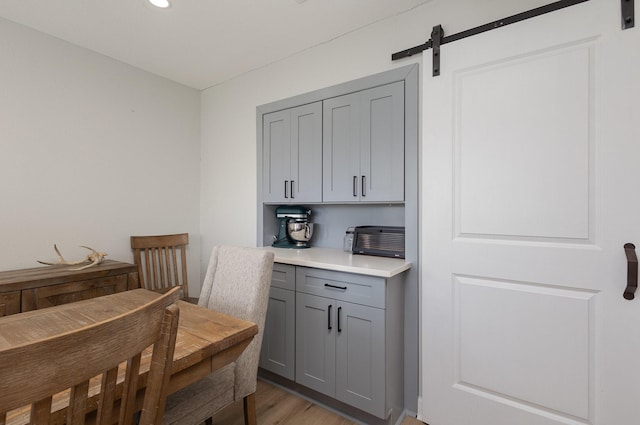 bar with light wood finished floors, recessed lighting, and a barn door