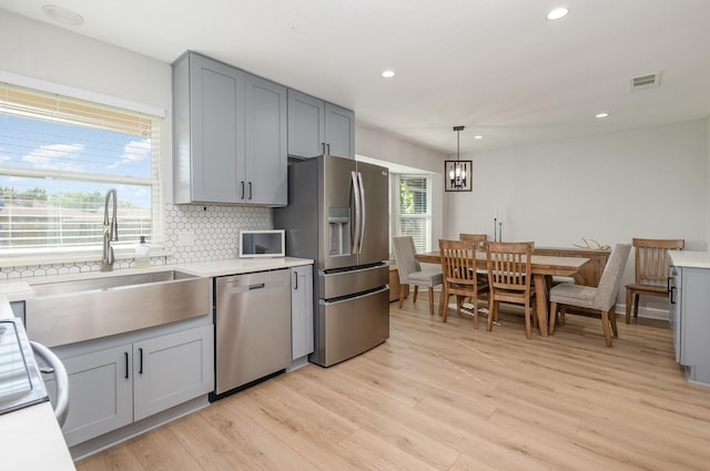 kitchen featuring appliances with stainless steel finishes, a sink, gray cabinetry, tasteful backsplash, and recessed lighting