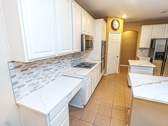 5320 Alta Loma Dr, Fort Worth, TX 76244 - kitchen featuring appliances with stainless steel finishes, arched walkways, tasteful backsplash, a center island, and white cabinetry