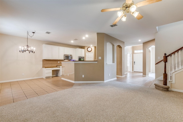 unfurnished living room with arched walkways, light tile patterned floors, ceiling fan with notable chandelier, light carpet, and recessed lighting