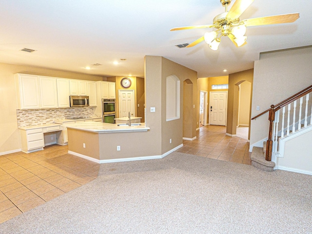 5320 Alta Loma Dr, Fort Worth, TX 76244 - kitchen featuring stainless steel appliances, arched walkways, light tile patterned floors, light colored carpet, and ceiling fan