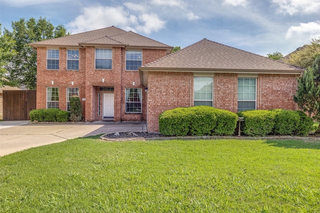view of front of home featuring fence, roof with shingles, a front lawn, and brick siding