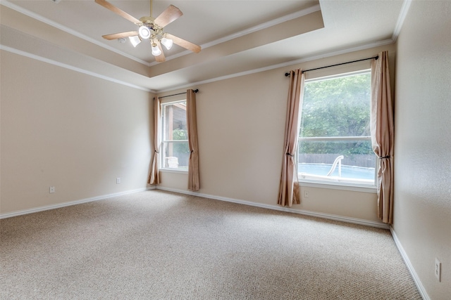 carpeted spare room featuring baseboards, ornamental molding, a tray ceiling, and ceiling fan