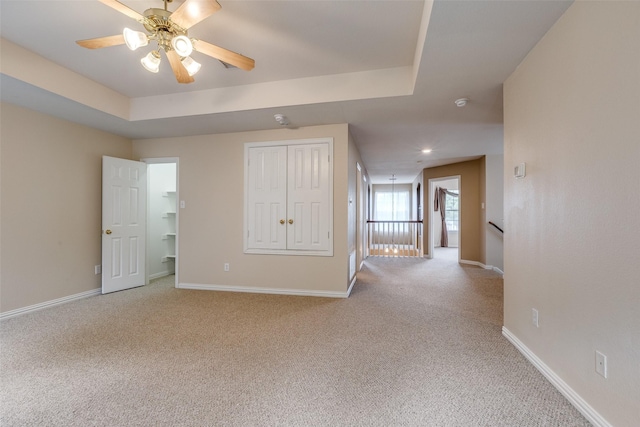 spare room featuring baseboards, ceiling fan, and light carpet