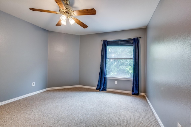 carpeted spare room featuring ceiling fan and baseboards