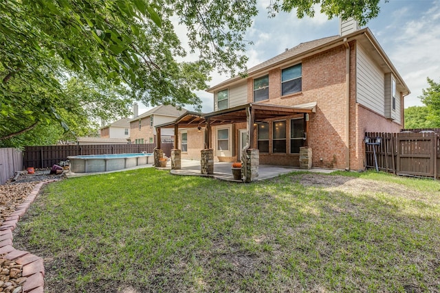 rear view of house featuring ceiling fan, a chimney, a lawn, brick siding, and a fenced backyard