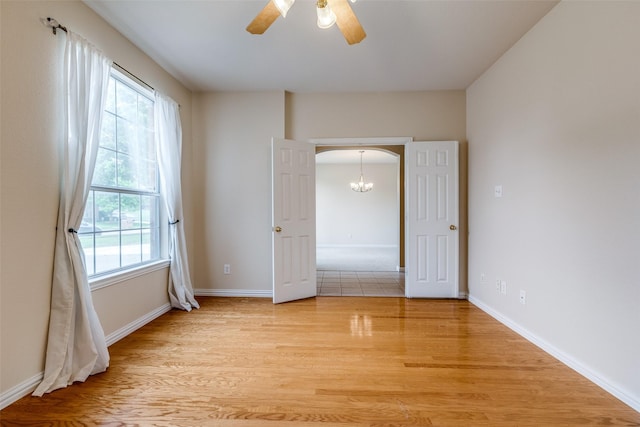unfurnished bedroom featuring arched walkways, baseboards, multiple windows, and light wood-style floors