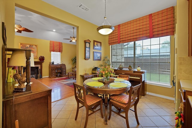 dining area featuring light tile patterned flooring, ceiling fan, a fireplace, baseboards, and visible vents