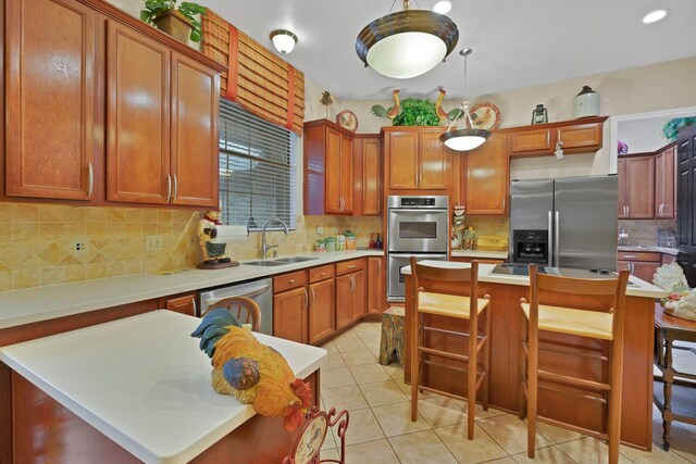 kitchen featuring a breakfast bar area, backsplash, appliances with stainless steel finishes, a center island, and a sink