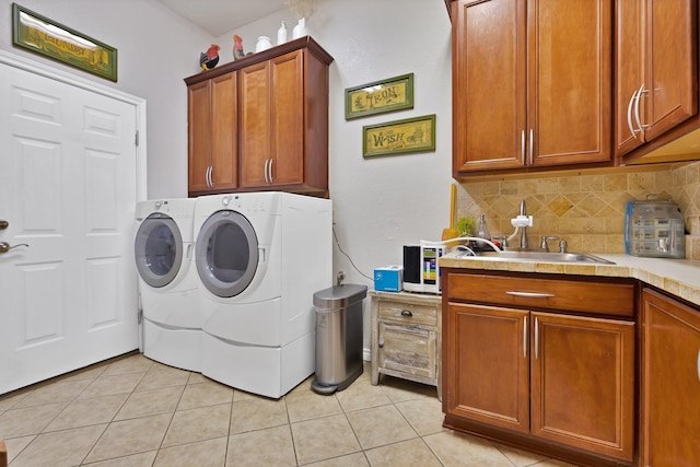 clothes washing area with a sink, cabinet space, light tile patterned floors, and washer and dryer