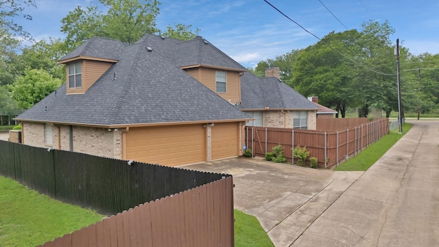 view of home's exterior with brick siding, fence, and roof with shingles