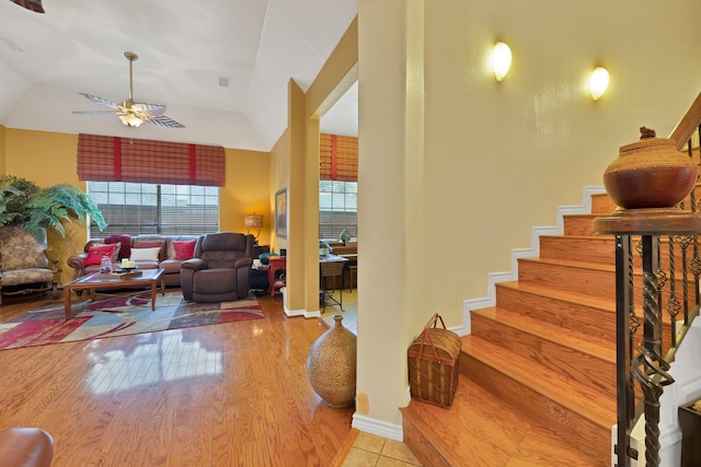 stairs with a ceiling fan, visible vents, wood finished floors, and lofted ceiling