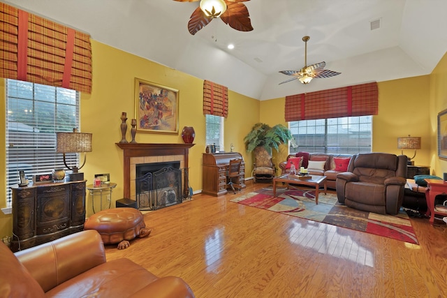living room featuring vaulted ceiling, a ceiling fan, wood finished floors, and a tile fireplace