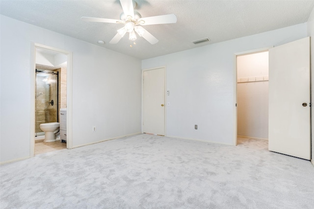 unfurnished bedroom with a spacious closet, light carpet, a textured ceiling, and visible vents
