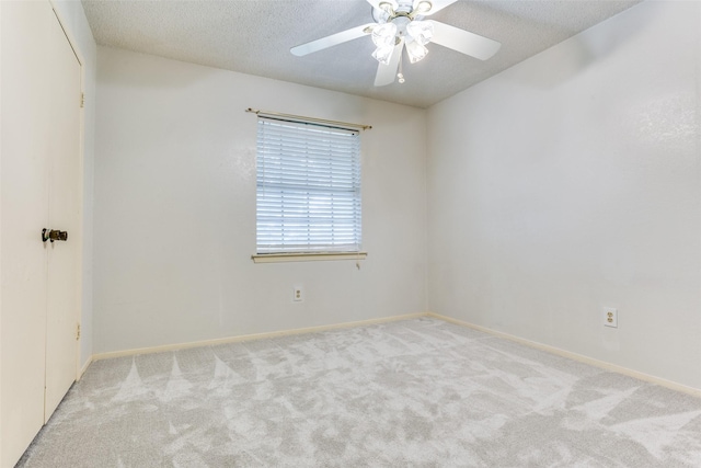 carpeted spare room with baseboards, ceiling fan, and a textured ceiling
