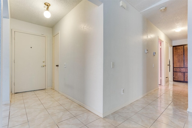 corridor with light tile patterned floors and a textured ceiling