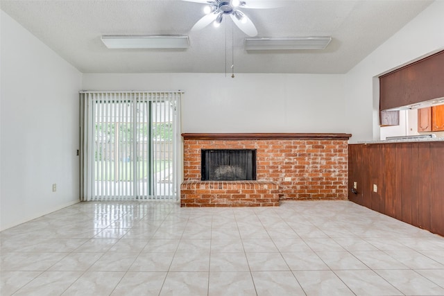 unfurnished living room featuring a brick fireplace, a ceiling fan, a textured ceiling, and light tile patterned flooring