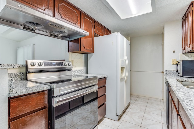 kitchen featuring under cabinet range hood, tasteful backsplash, light stone counters, appliances with stainless steel finishes, and light tile patterned floors